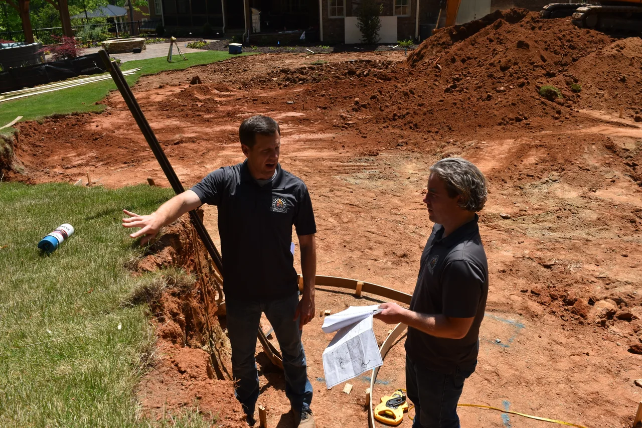 Hearthstone team reviewing blueprints on a job site Hearthstone team members reviewing project blueprints on site during pool construction