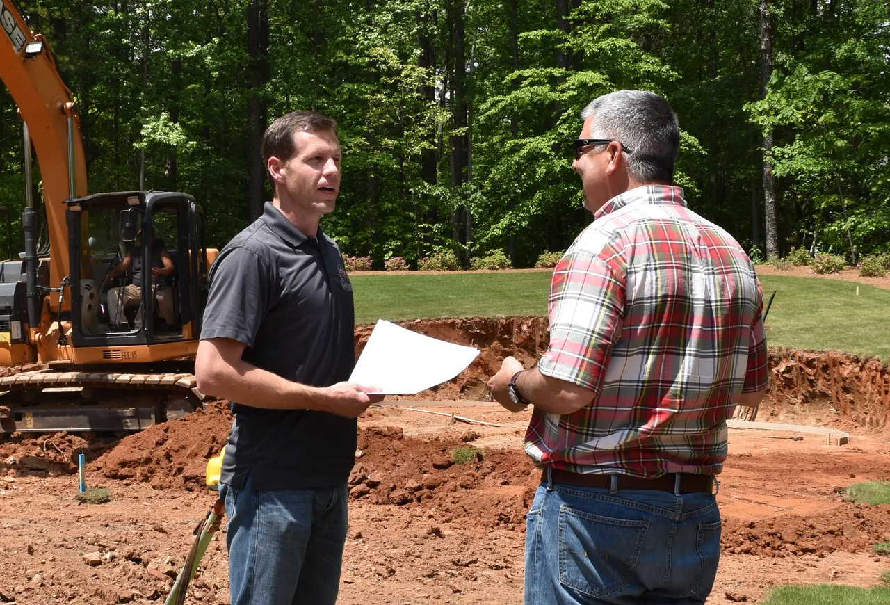 Hearthstone designer reviewing pool plans with a client at a consultation