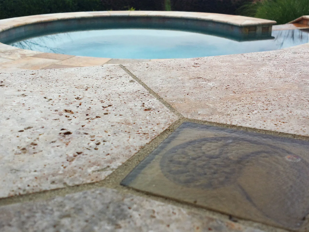 Travertine pool deck with sun shelf water feature meeting curved pool edge in Johns Creek, GA