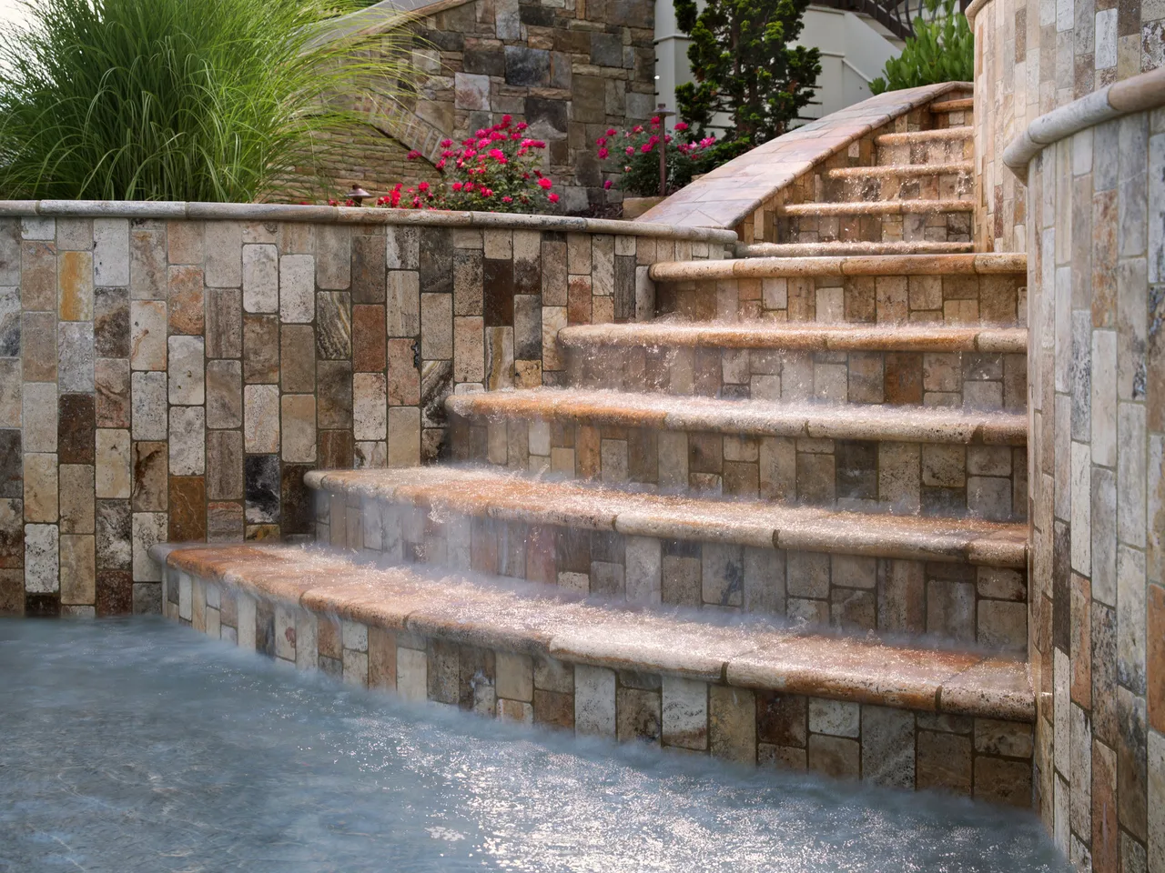 Tiered travertine steps with mixed stone retaining wall and ornamental landscaping in Johns Creek, GA