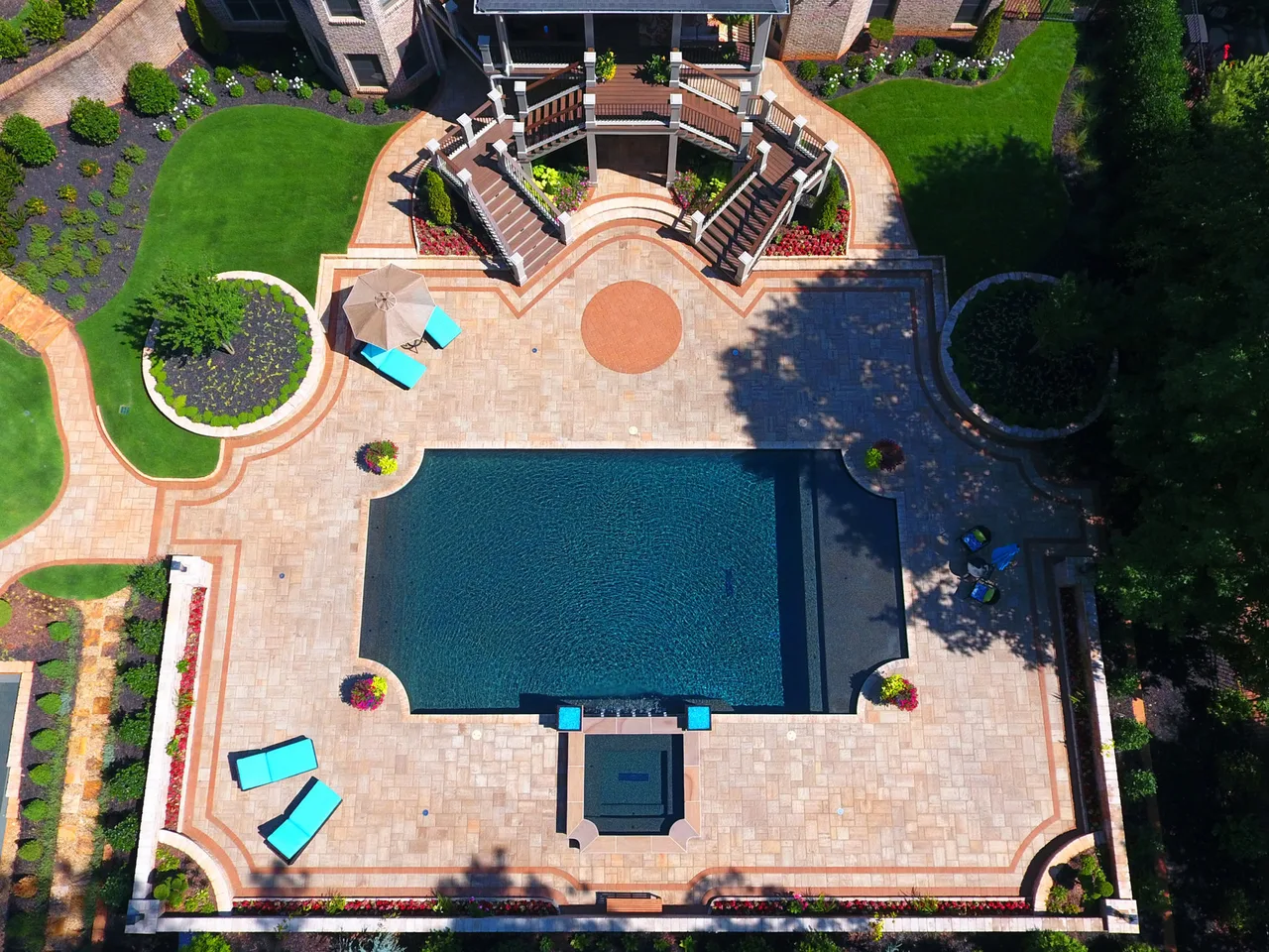 Overhead view of rectangular swimming pool with vanishing edge, travertine deck, spa, and symmetrical lounge areas in Marietta, GA