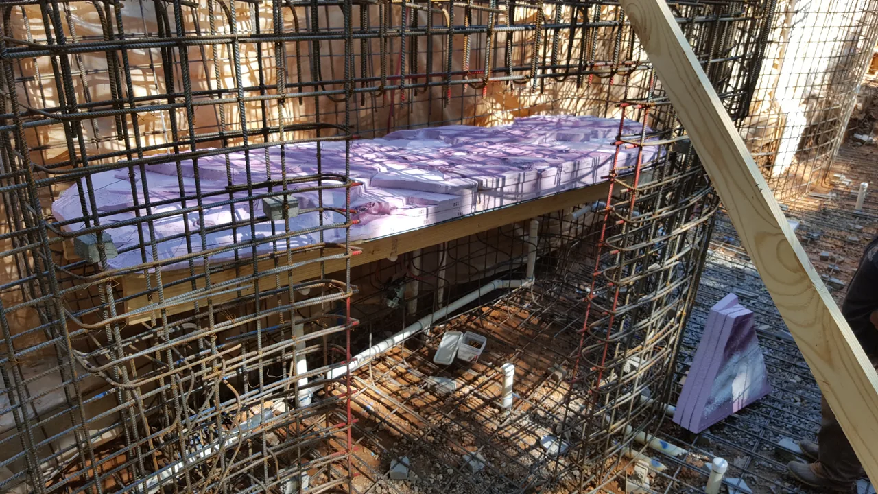 Reinforced steel rebar framework for vanishing edge spa construction with concrete forming boards and protective tarps, Marietta Georgia