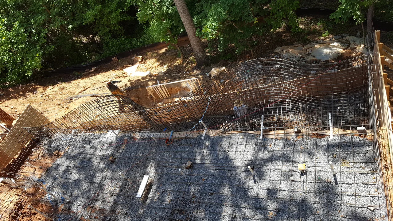 Rebar reinforcement grid laid across concrete pool foundation with tree shade in Marietta Georgia